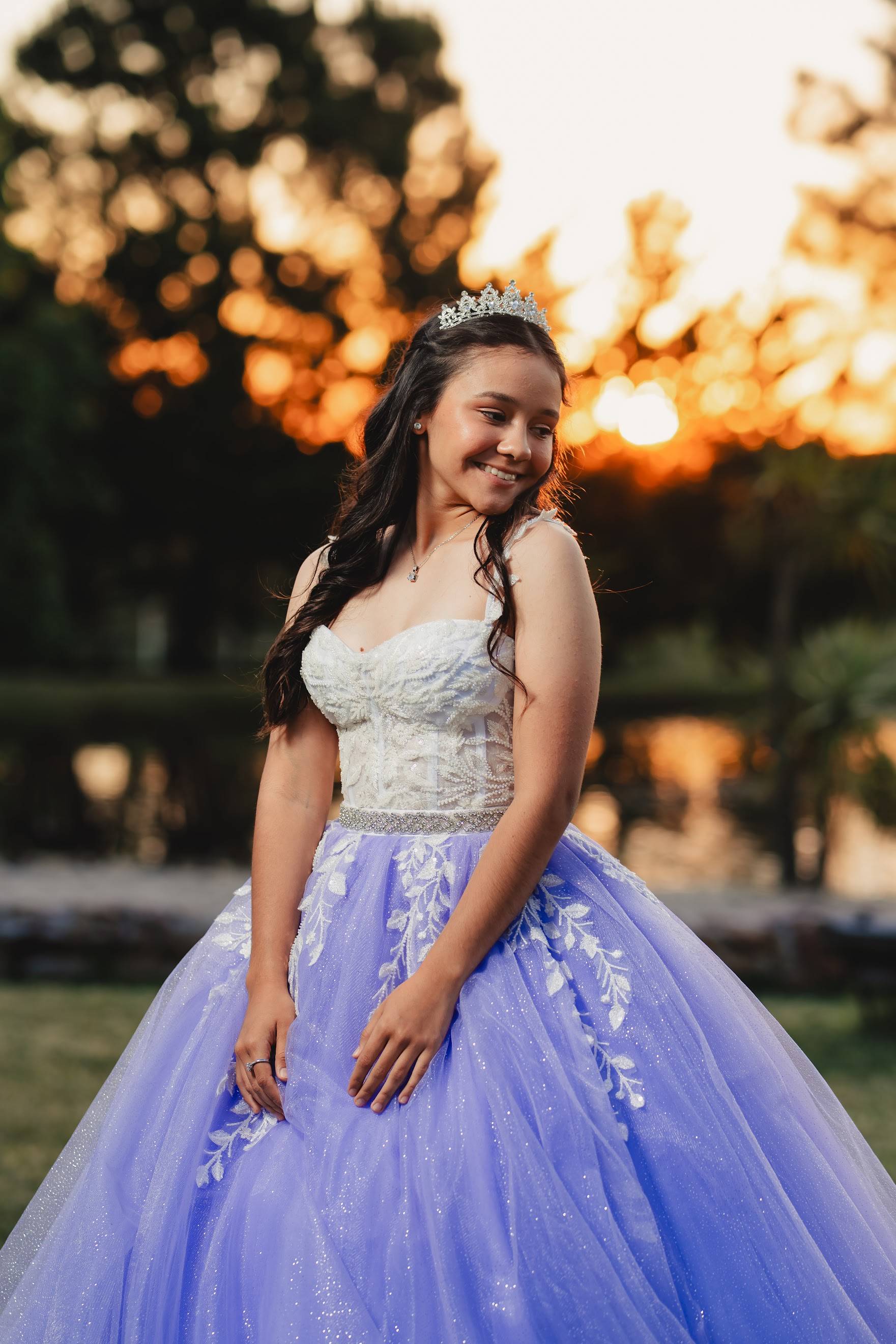 Vestido de 15 con corset claro bordado, tirantes, cinturón de pedrería y falda lila de tul con apliques de hojas